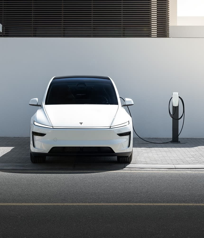Tesla Model Y warna putih, diparkir di pengecas rumah