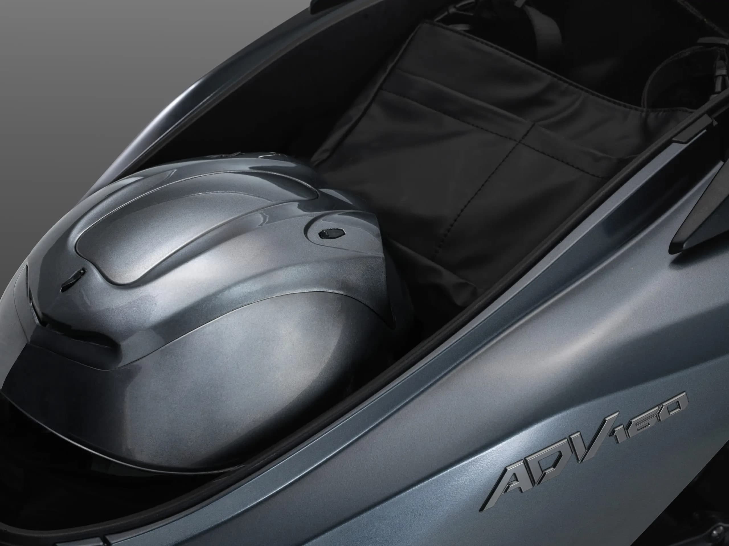 Ruang simpanan 30 liter Honda ADV160 terbuka dengan topi keledar muka penuh, lencana ADV160 pada badan belakang