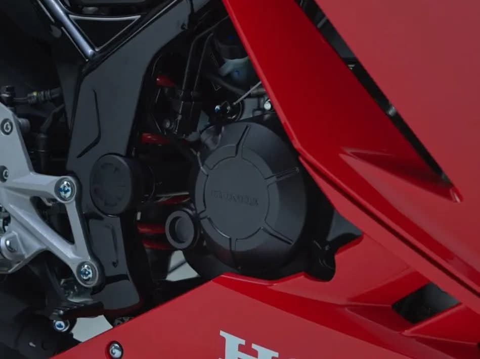 Penutup enjin dan klac Honda CBR150R dengan badan merah di latar belakang