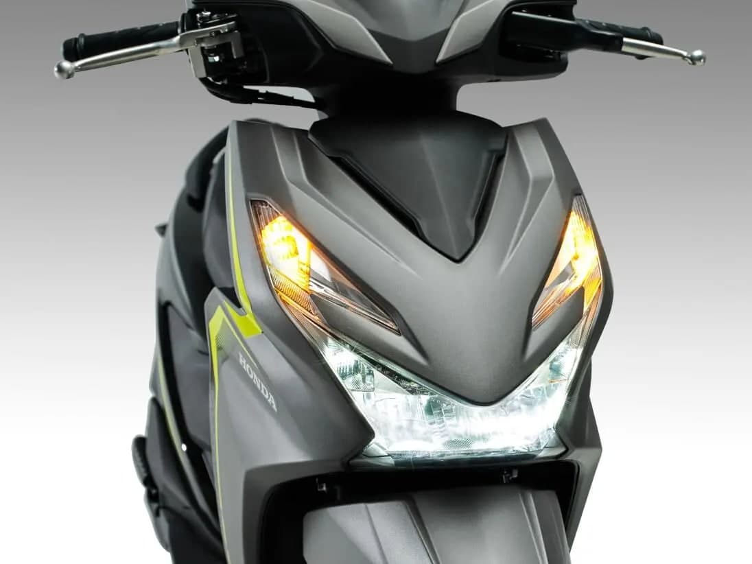 Lampu utama LED Honda BeAT menyala pada badan kelabu gelap dengan jalur hijau lime